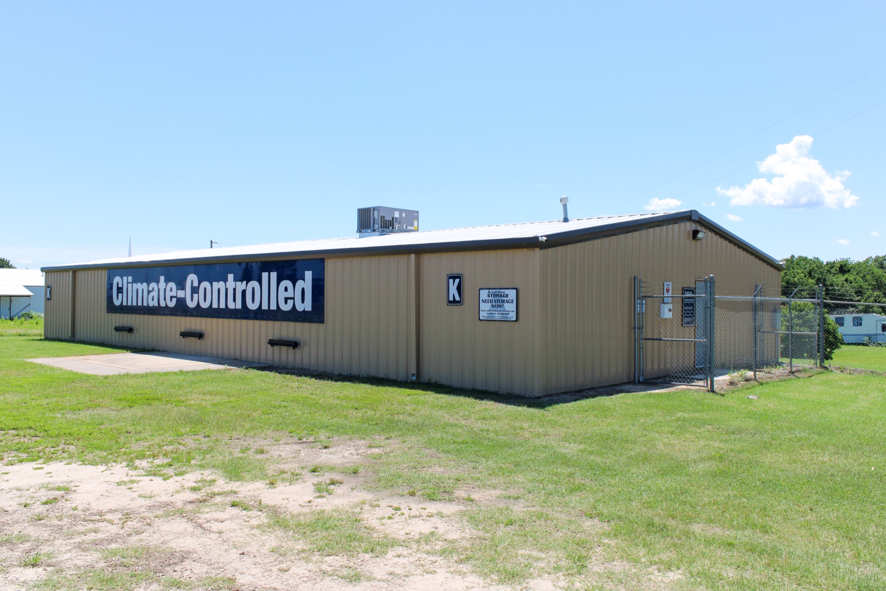 Ground-level view of Arborstone Storage Eufaula II, a tan climate-controlled building with the navy Climate-Controlled banner across the side.