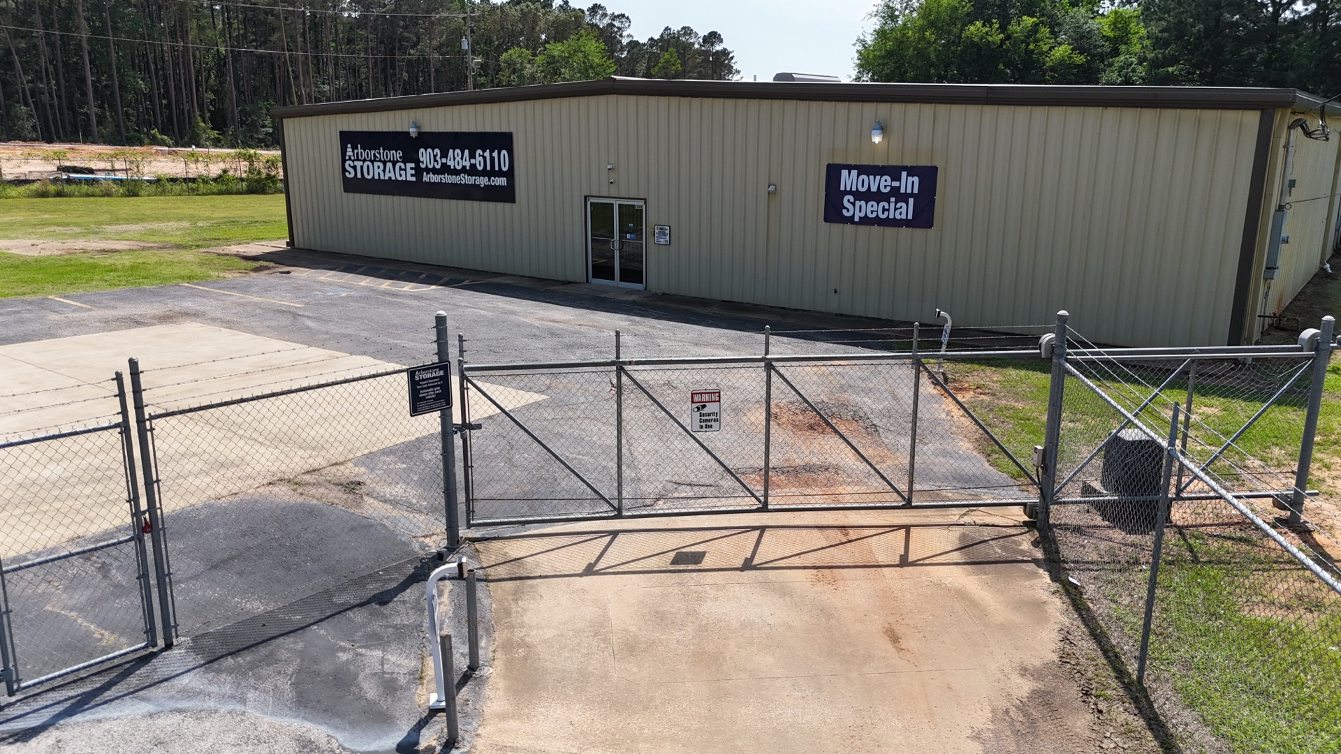 Arborstone Storage Longview building entrance on Jahan Trail — tan metal building with Arborstone Storage signage, 903-484-6110 phone number, Move-In Special banner, and a chain-link security gate.