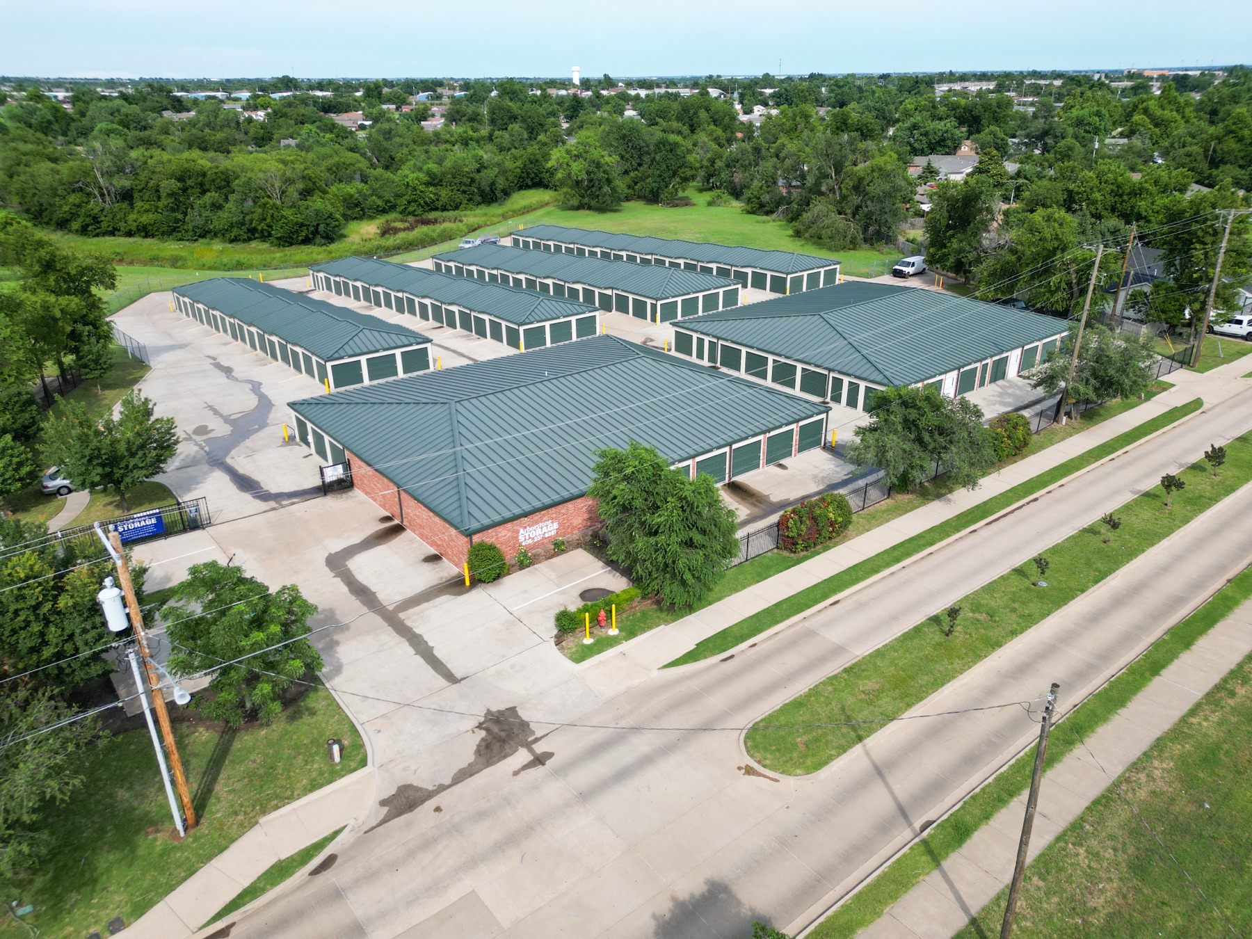 Aerial view of Arborstone Storage Moore, showing multiple rows of drive-up units with green roofs and a brick office next to a divided suburban street.