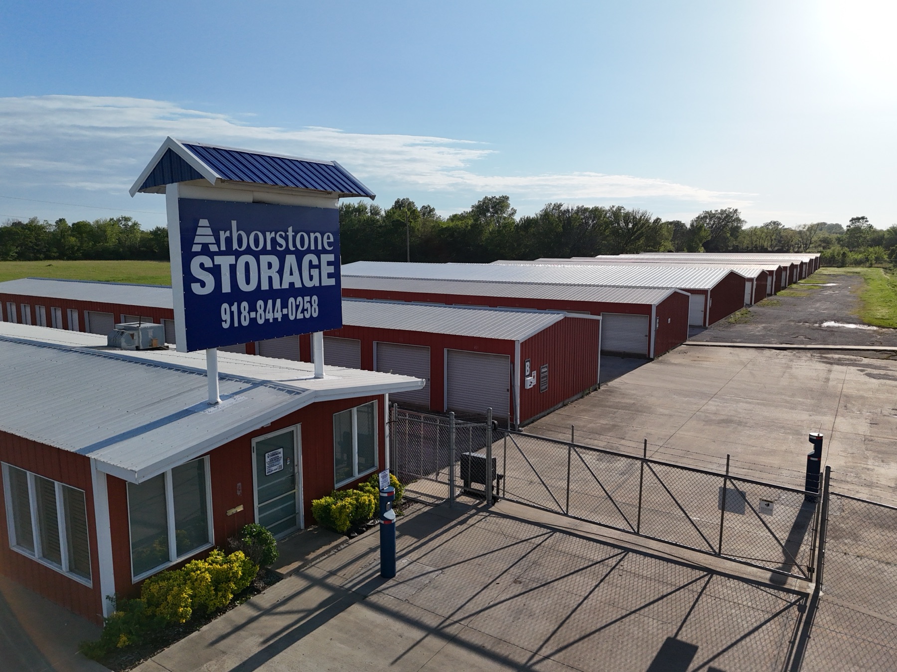 Aerial view of Arborstone Storage Okmulgee II showing multiple rows of red drive-up units and the Arborstone Storage entrance sign.