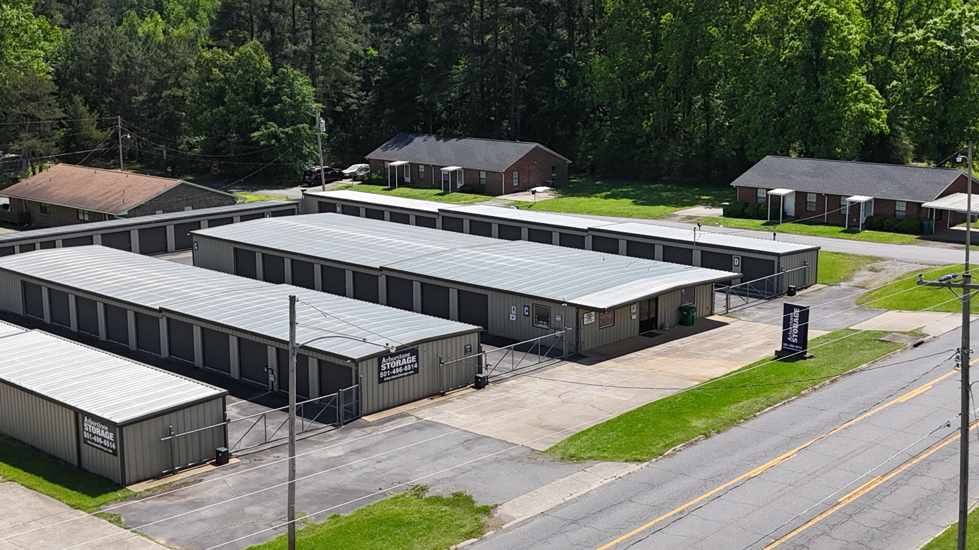 Aerial view of Arborstone Storage Redfield I — tan metal drive-up storage buildings with pitched gray roofs along Sheridan Rd in Redfield, Jefferson County, Arkansas.