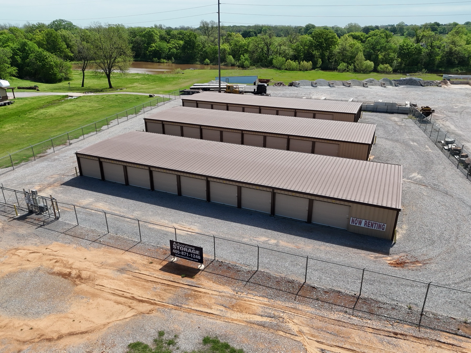 Aerial view of Arborstone Storage Tecumseh II showing a long row of white drive-up units with red trim next to a large concrete drive and the Arborstone Storage sign.