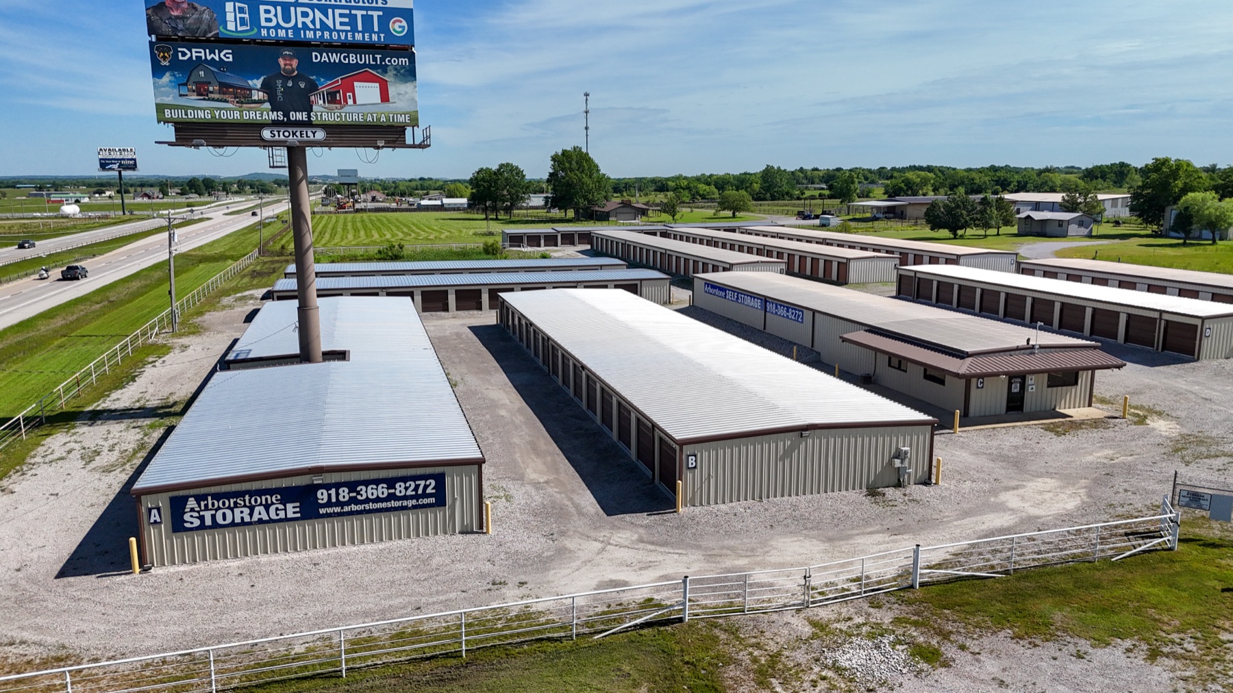 Aerial view of an Arborstone Storage facility in the Tulsa metro, drive-up storage units next to a highway with a lit Arborstone Storage sign.