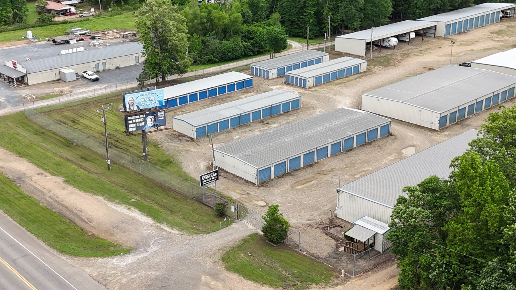 Aerial view of Arborstone Storage Broken Bow on US-259: rows of blue-door drive-up units, covered RV parking and the Arborstone Storage sign at the gated entrance.