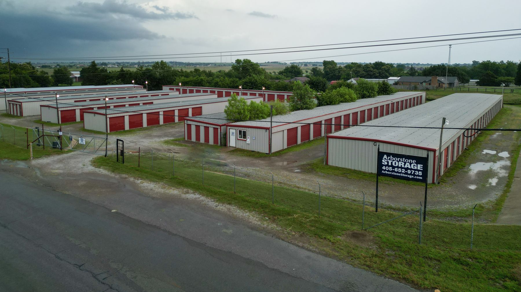 Aerial view of Arborstone Storage Elgin: rows of drive-up storage buildings with red doors and the Arborstone Storage sign beside NE Tony Creek Rd.