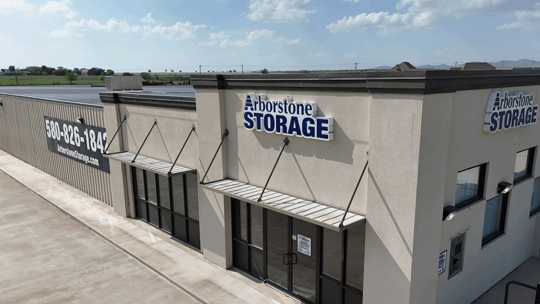 Arborstone Storage Lawton: the stucco office building with Arborstone Storage signs and the long climate-controlled storage building beside it.