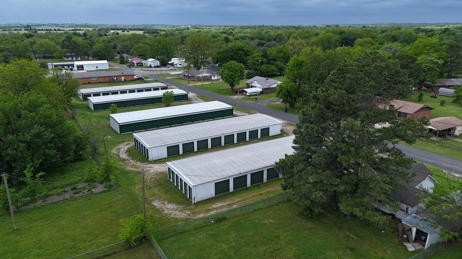 Aerial view of Arborstone Storage Stratford: rows of white drive-up storage buildings with green doors among trees on N. Pecan Ave.