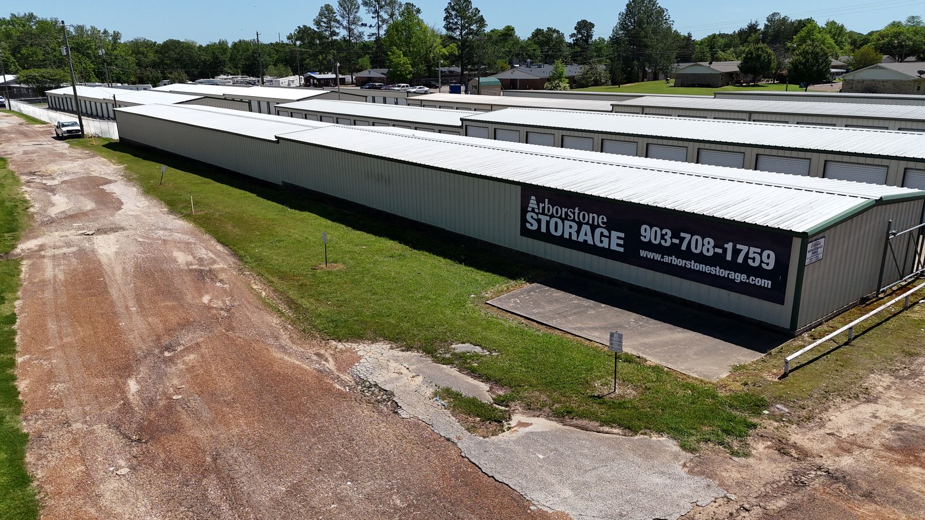 Aerial view of Arborstone Storage Winnsboro: long white storage buildings with the Arborstone Storage sign and phone number on the end wall.