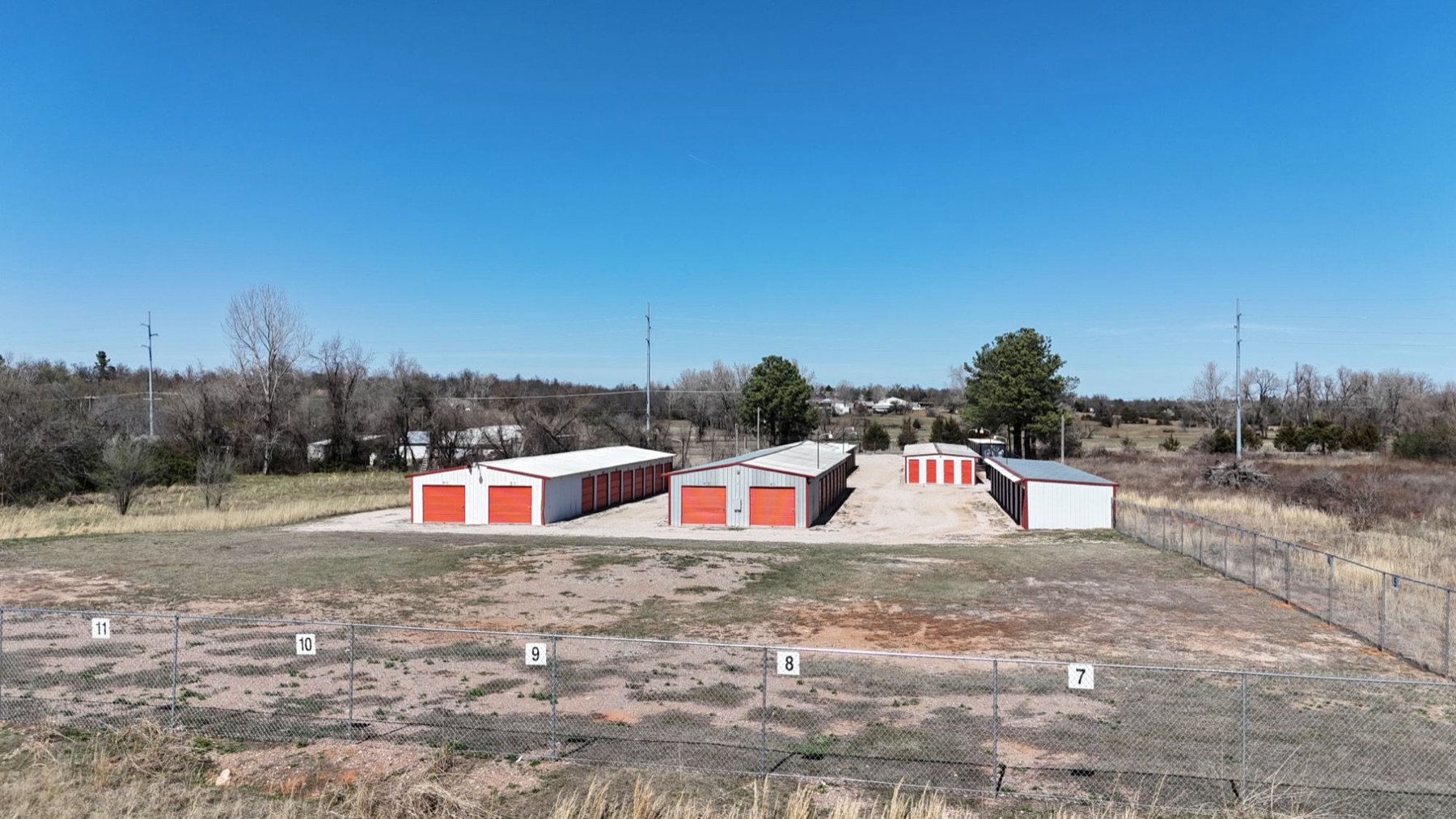 Drive-up storage buildings with red roll-up doors inside a fenced perimeter at the Arborstone Storage Choctaw facility