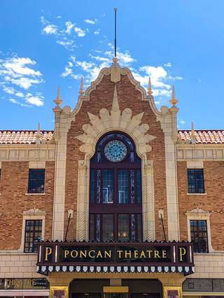 The brick-and-terra-cotta facade of the Poncan Theatre in downtown Ponca City, with a stained-glass rose window above the Poncan Theatre marquee.