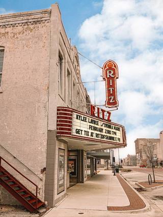 The Ritz Theatre on Main Street in downtown Shawnee: a vertical red RITZ sign and a lettered marquee on a two-story stucco building.