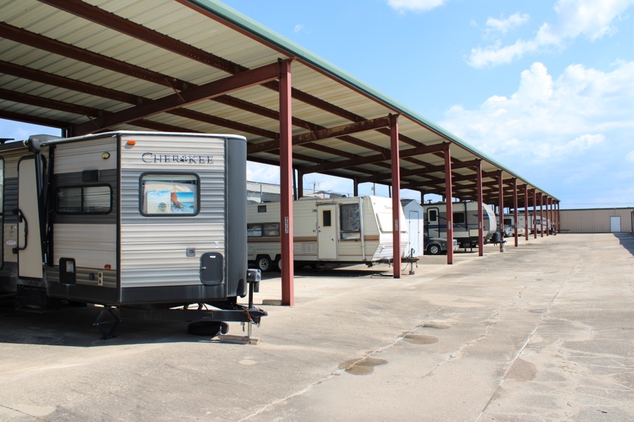 Travel trailers and RVs parked under a steel covered-parking canopy