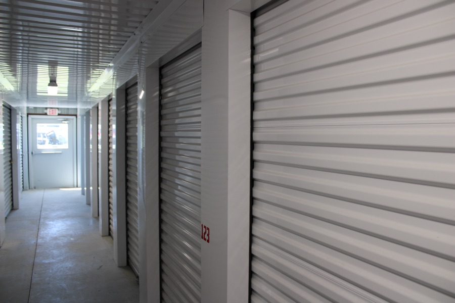 Interior hallway of indoor storage units with white roll-up doors