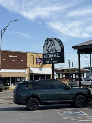 The Buffalo Grill sign, with a bison head and "EST 2016", on a downtown Hugo street of brick storefronts.